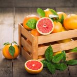 grapefruits in a wooden box with leaves